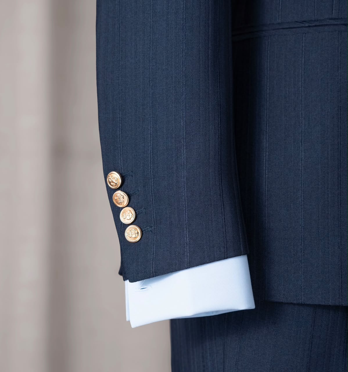 Four gold-tone sleeve buttons above a pale blue shirt cuff