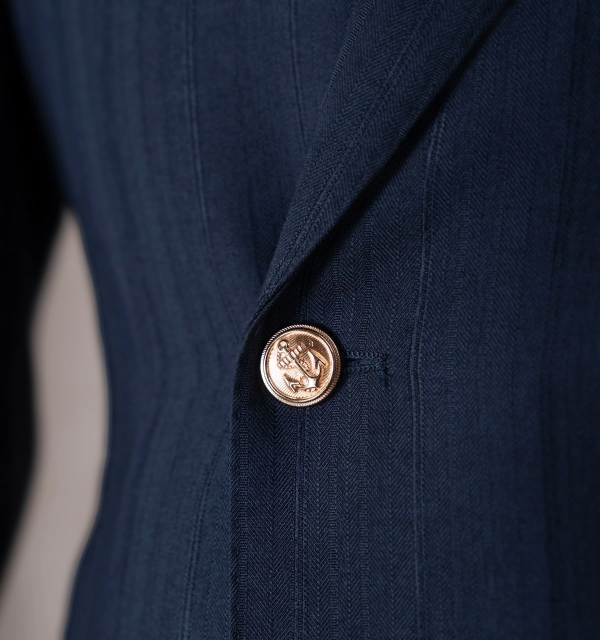 Gold-tone embossed button against textured navy fabric